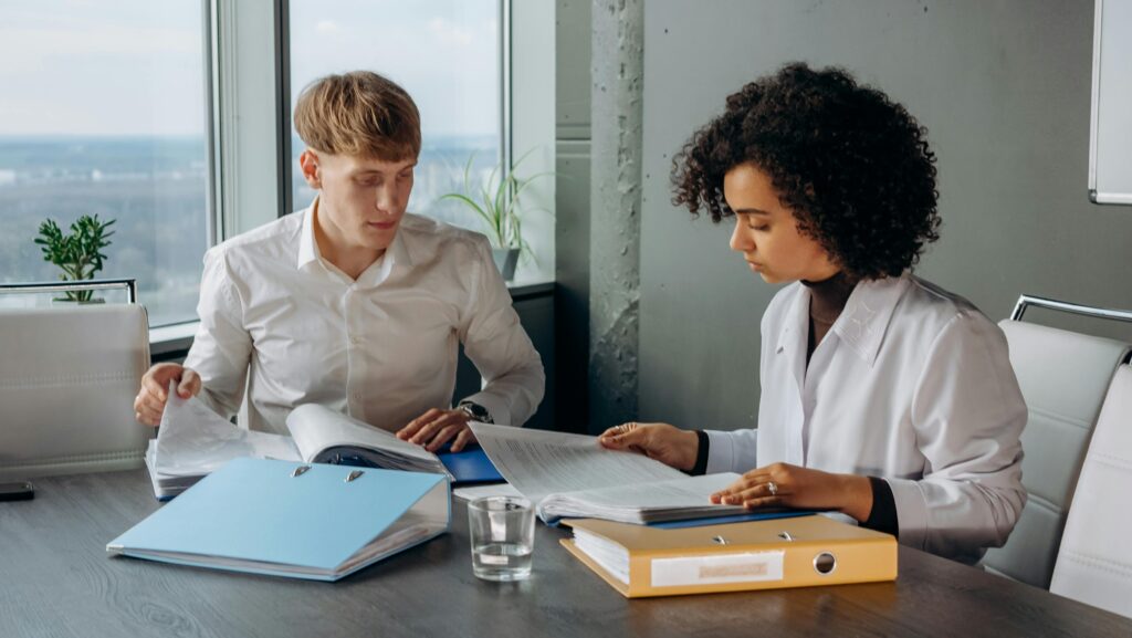 pexels-photo-8297474-8297474 Two business colleagues analyzing financial reports at a desk in a modern office environment.